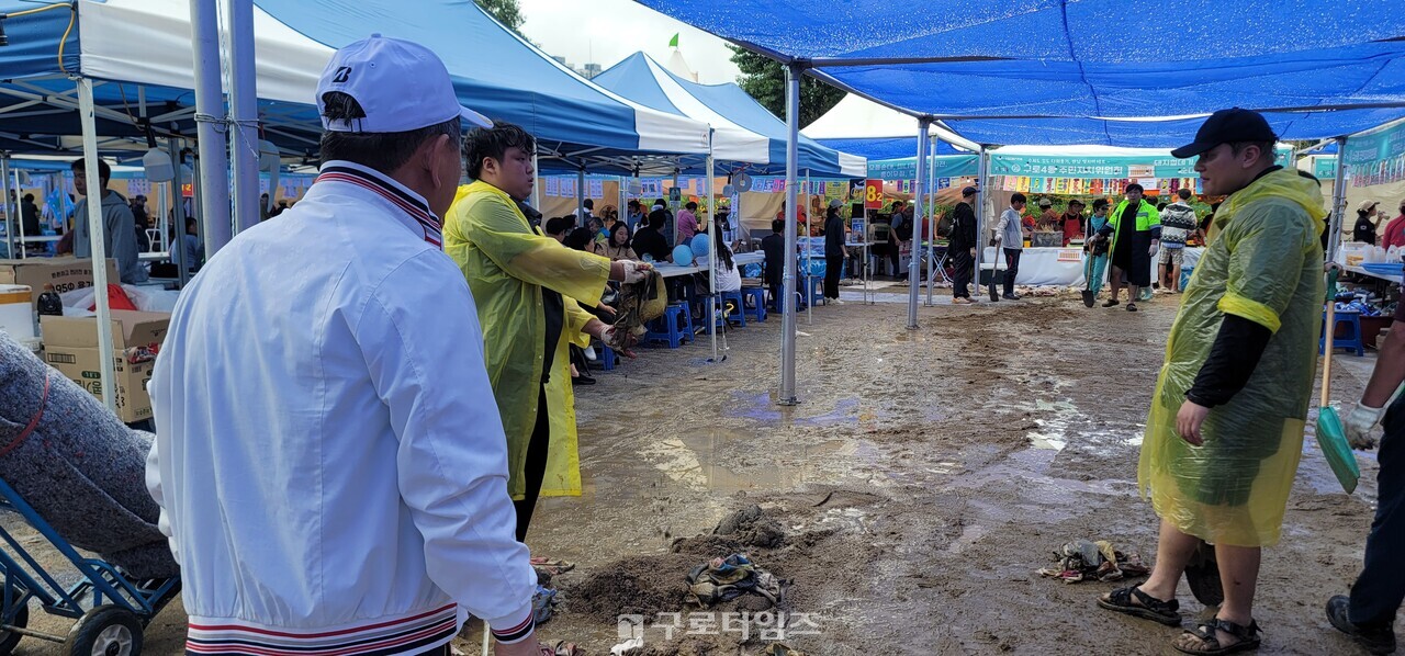 안양천 축구장에 설치된 각동주민자치위원회의 먹거리장터. 밤새 내린 비로 발목까지 오른 빗물이 어느정도 빠진후 진입통로에 배수로공사후 부직포를 깔준비를 하고 있다. 마정일 구로구주민자치위원장협의회장이 치수과직원들과 현장공사를 진행하고 있다. 
